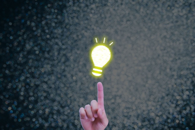 光る電球をさす人差し指